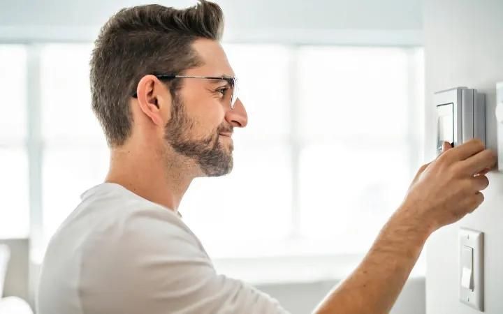 homme réglant son thermostat