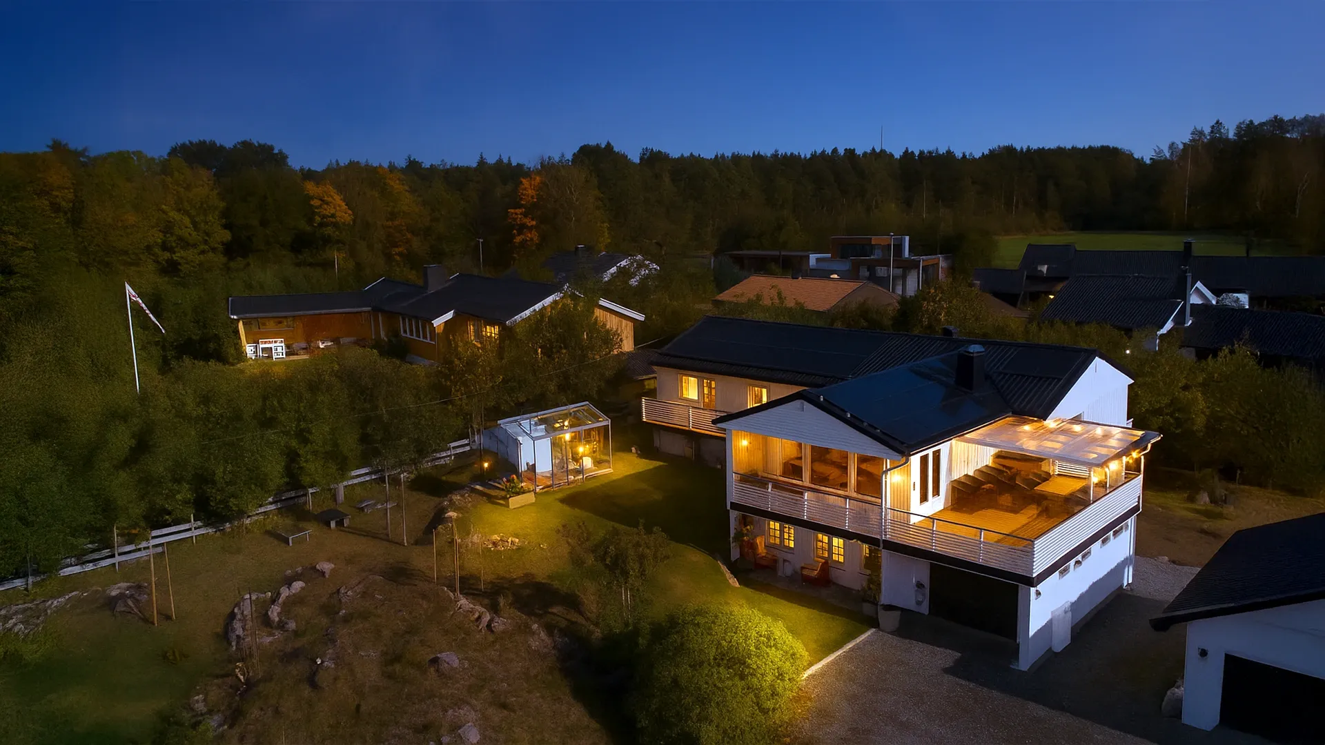 Maison avec panneaux solaires illuminée la nuit, entourée d'arbres